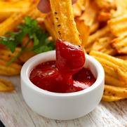 Homemade potato ridge chips, fries with ketchup on white wooden board